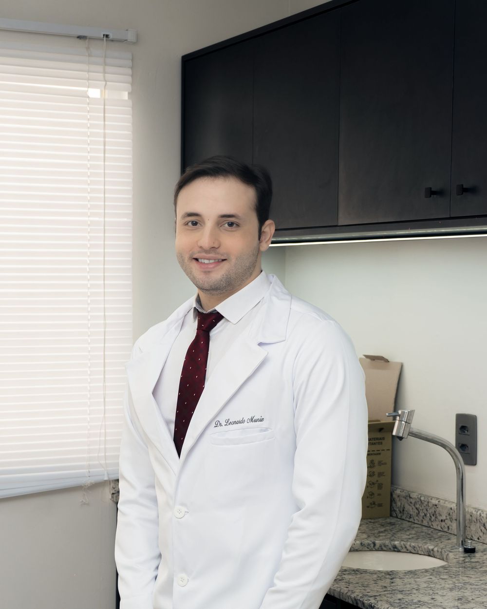 A physician practice owner standing confidently in his office