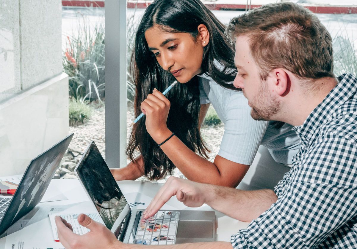 Two colleagues reviewing account work together at their laptops