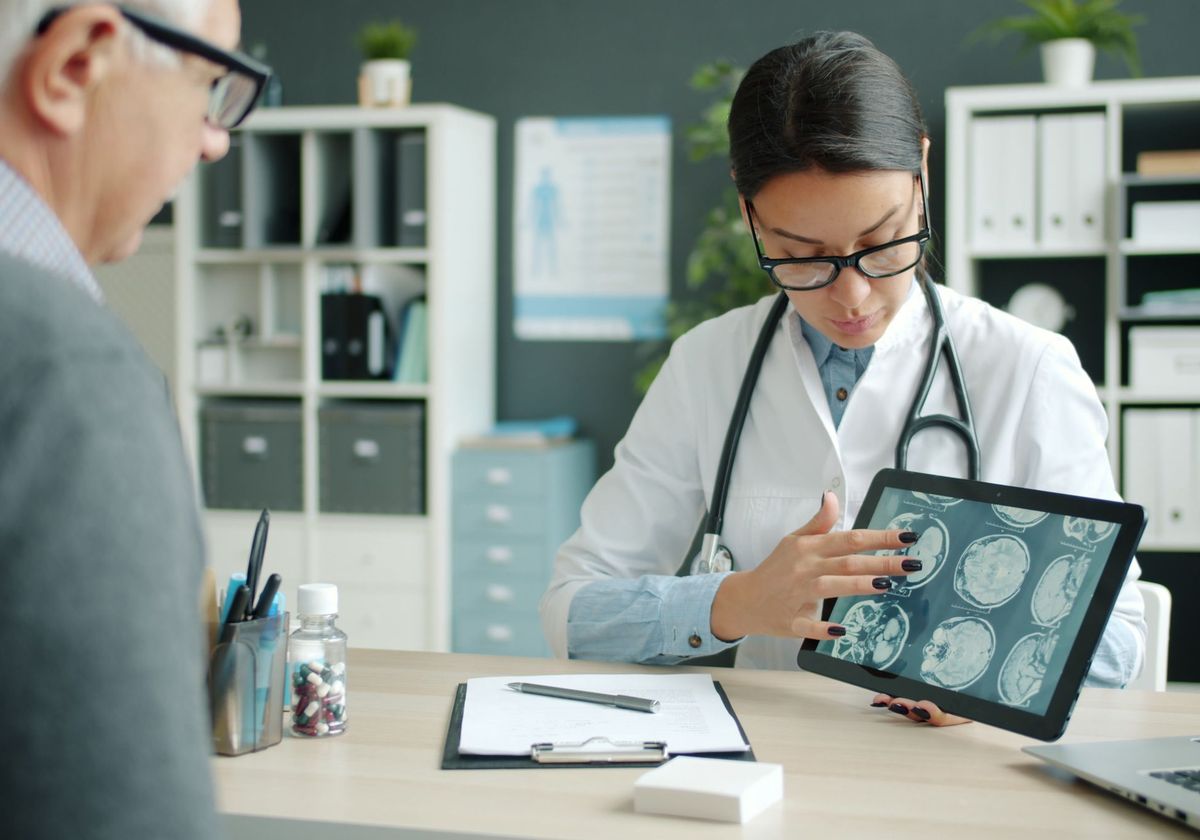 A neurologist reviewing brain scans on a tablet during a consultation