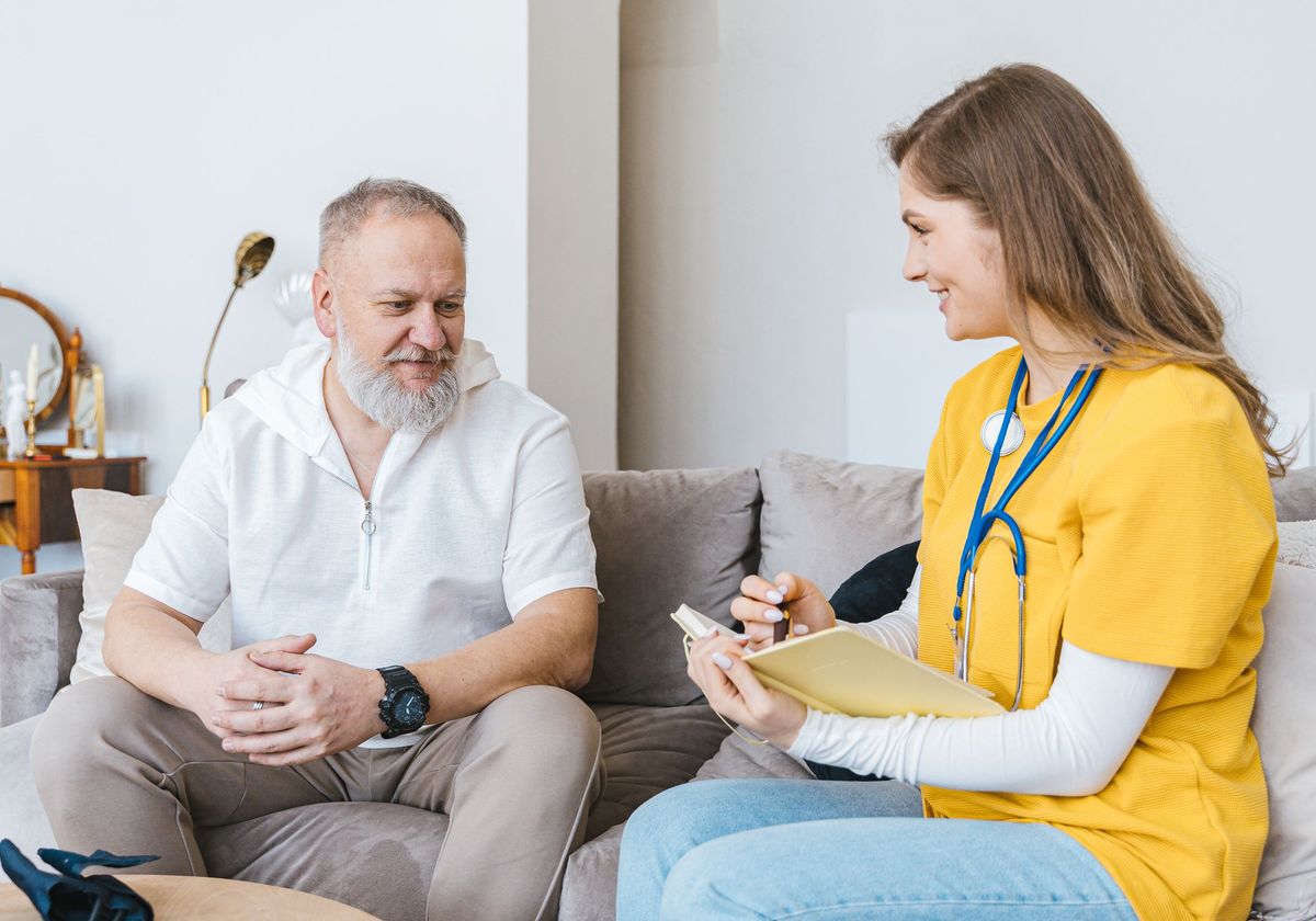 A clinician smiling with an older patient during a home visit