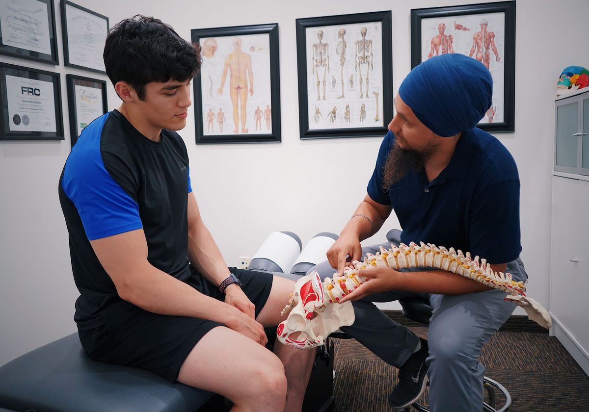 A physician using a spine model to explain back pain to a patient