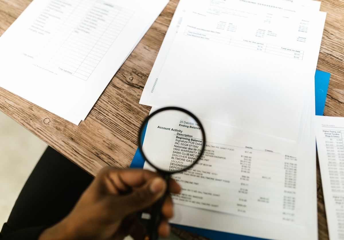 An auditor checking billing records with a magnifying glass