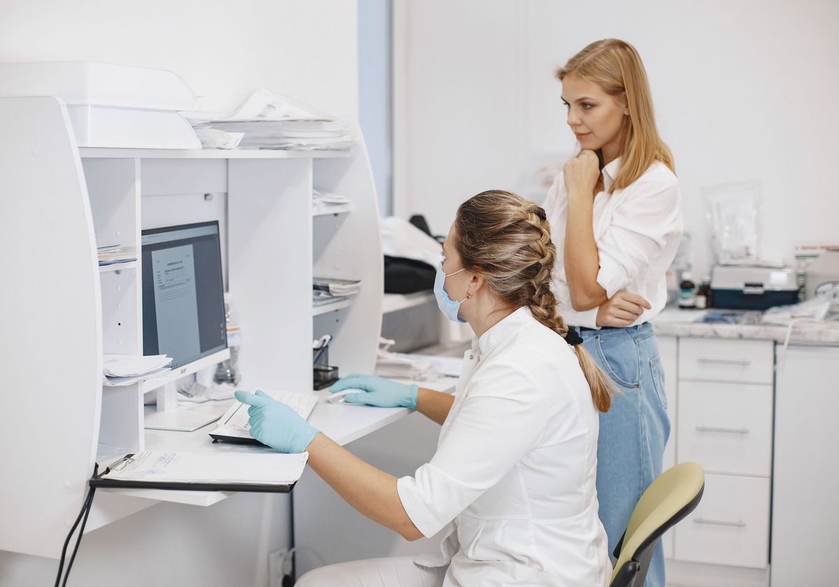 Two billing specialists reviewing claims on a computer in a clinic office