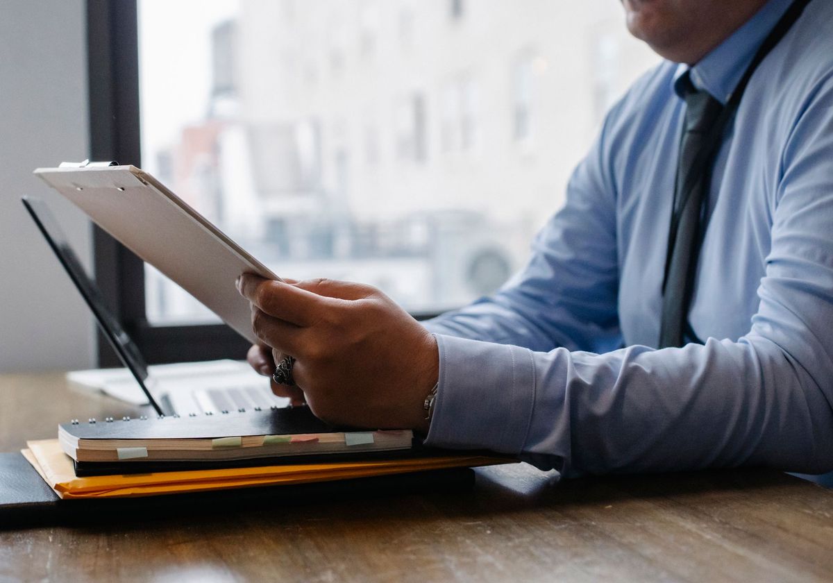 A coding specialist reviewing a patient record on a tablet at his desk