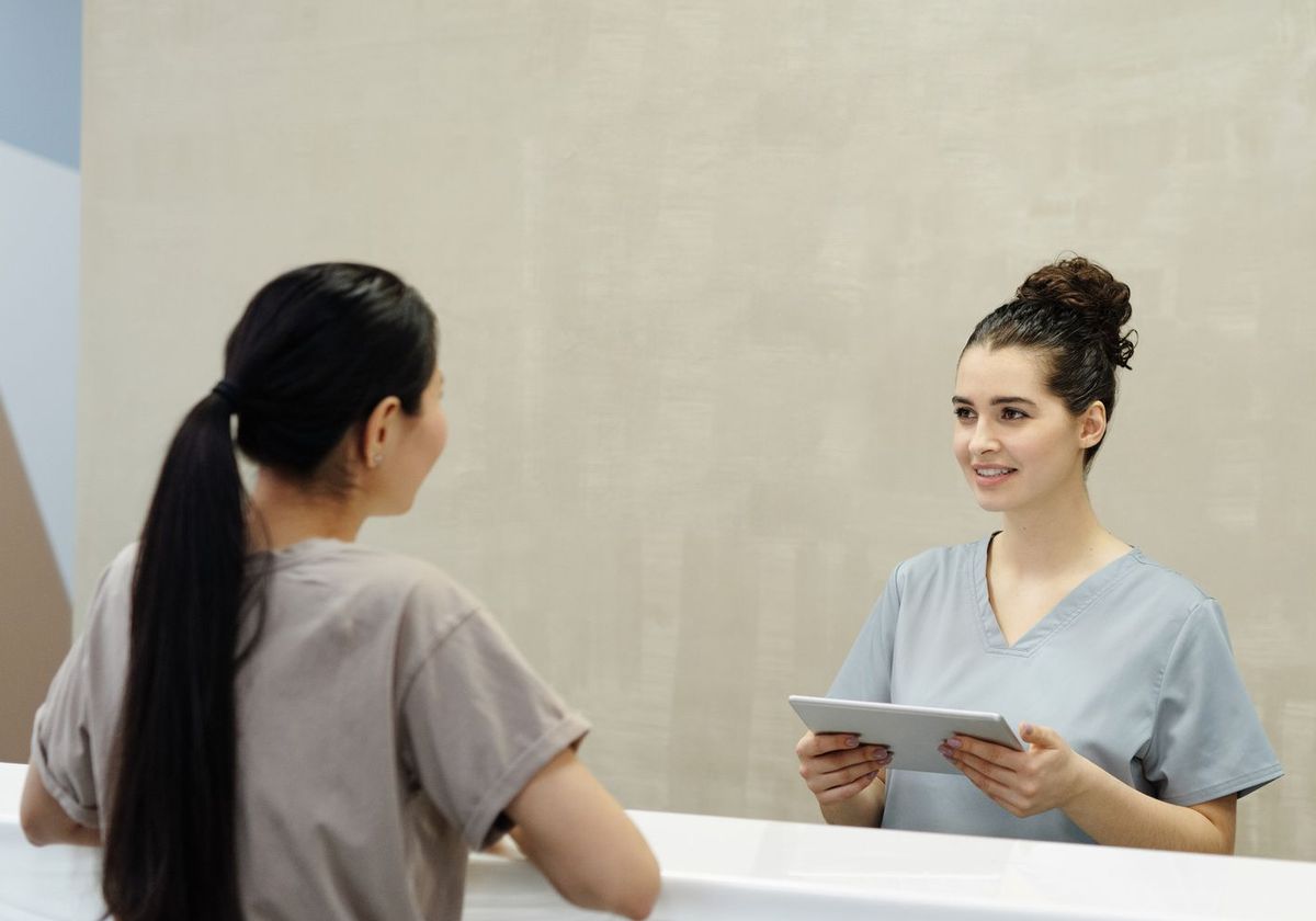 A front-desk coordinator checking in a patient with a tablet